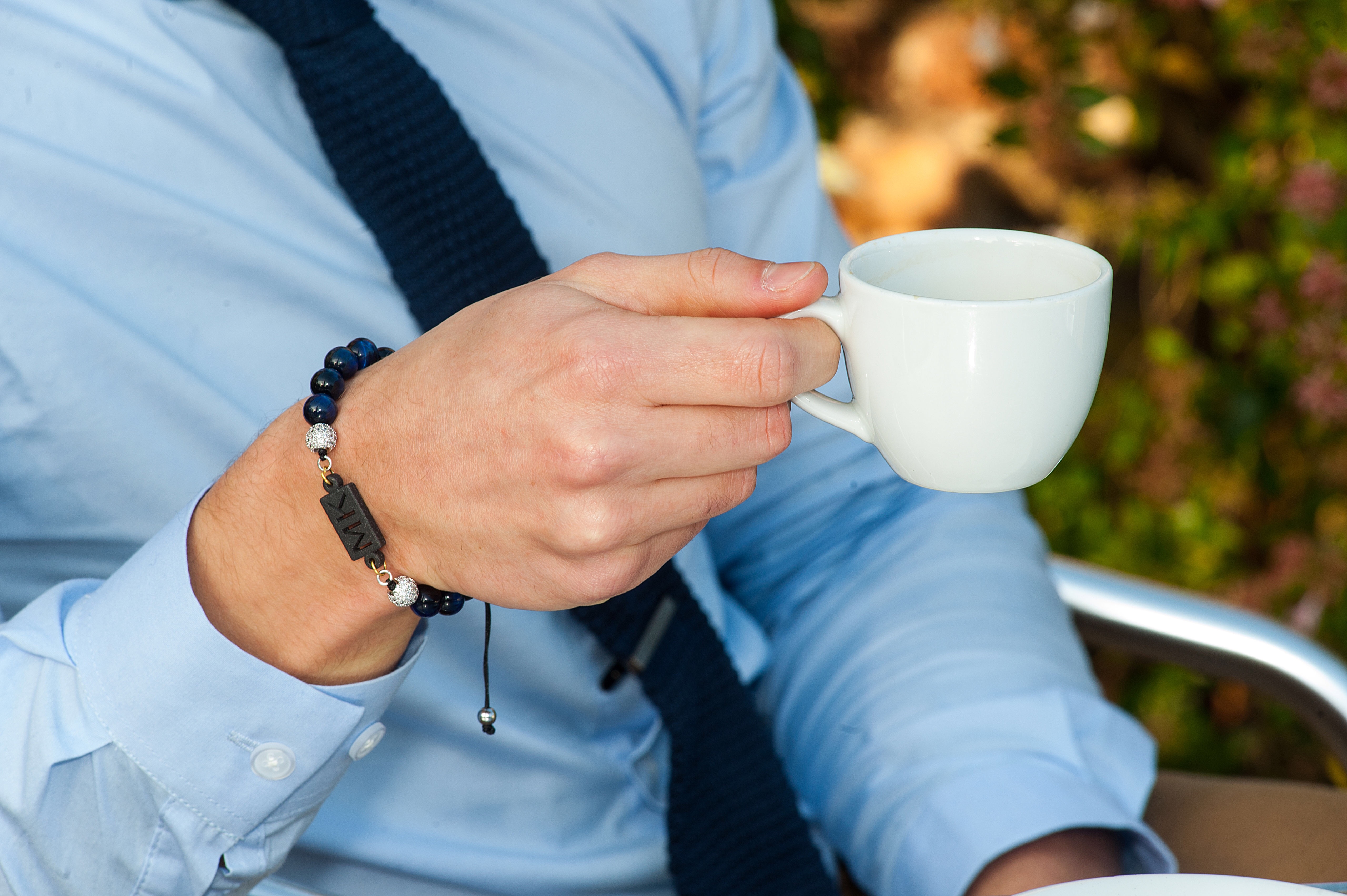 Man in smart suit wearing a bracelet drinking coffee